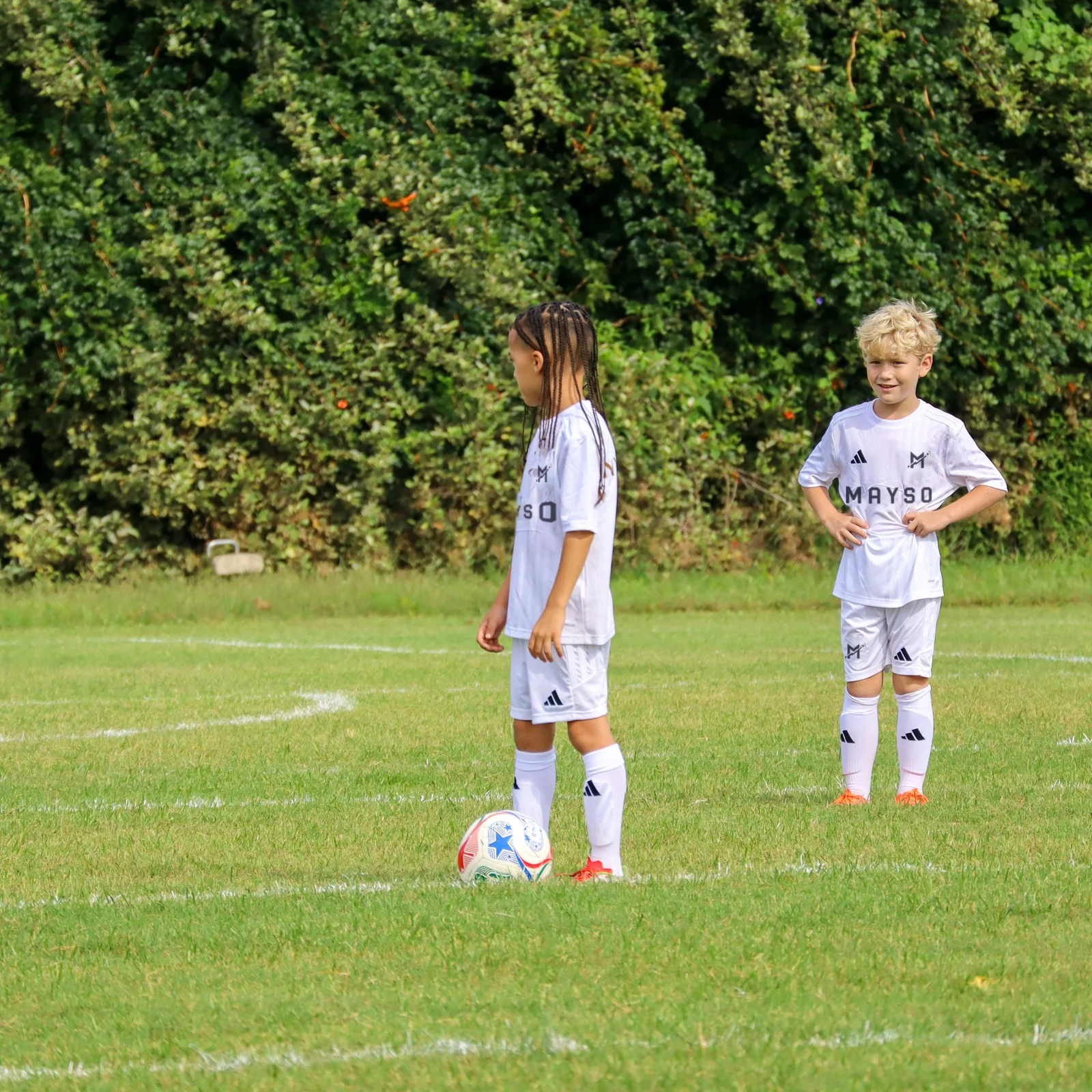 MAYSO players in the club’s white kits on an outdoor grass field